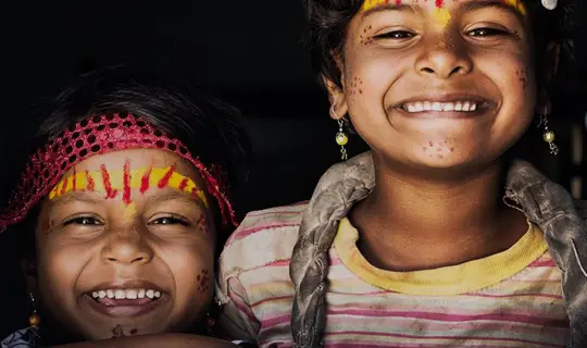 Two children smiling through wooden door